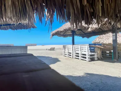 a beach with a straw umbrella and a bench at Casa Bita Morales CASA 201 in Cartagena de Indias