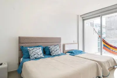a white bedroom with a large bed with blue pillows at Apartamento completo vacacional in Cartagena de Indias