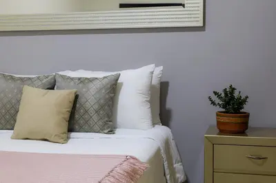 a bed with white pillows and a plant on a night stand at Casa Palmar Cartagena in Cartagena de Indias