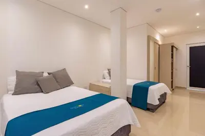 a bedroom with two beds and a tv at Amazing Beach House 13BR w/Pool & Staff in Cartagena de Indias