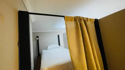 a bedroom with a bed and a yellow curtain at Capitel Hostel in Cartagena de Indias