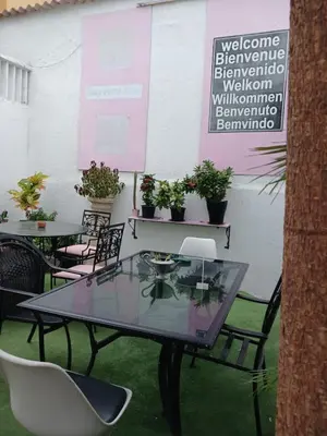 a glass table and chairs in a room with plants at Hostel Mamy Dorme in Barranquilla