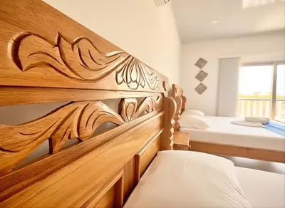 a bedroom with two beds and a wooden headboard at Tintipan Hotel in Tintipan Island