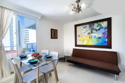 a living room with a table and a painting on the wall at AL-1C APARTAMENTO DE 1 ALCOBA CERCA AL MAR AIRE ACONDICIONADO WIFi Y PISCINA in Cartagena de Indias