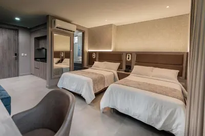a hotel room with two beds and a mirror at Amari Living Suites in Barranquilla