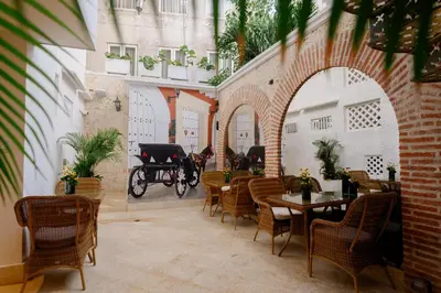 a patio with tables and chairs and a horse drawn carriage at Hotel Casa del Gobernador in Cartagena de Indias