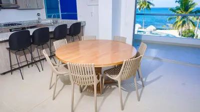 a wooden table and chairs in a kitchen with the ocean at Magico Apartamento Frente al Mar 4 Habitaciones PAZ335 in Coveñas