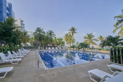 a swimming pool with white chairs and palm trees at Magico Apartamento Frente al Mar 4 Habitaciones PAZ335 in Coveñas