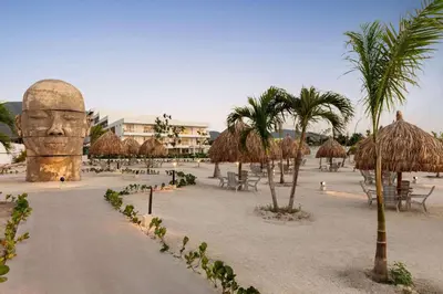 a beach with a statue of a head and palm trees at Wyndham Residences Santa Marta Aluna Beach Club in Santa Marta