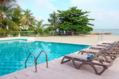 a swimming pool with lounge chairs next to a beach at Exclusiva casa en Baru con piscina y playa privada in Playa Blanca