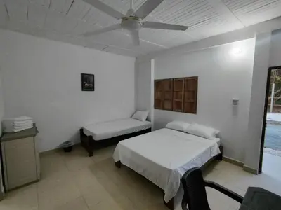 a bedroom with a bed and a couch and a ceiling fan at La Casa del Mar - Hotel Familiar en San Bernardo del Viento in San Bernardo del Viento