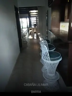 a row of white chairs sitting in a room at Cabaña Lilimar. in La Perdiz