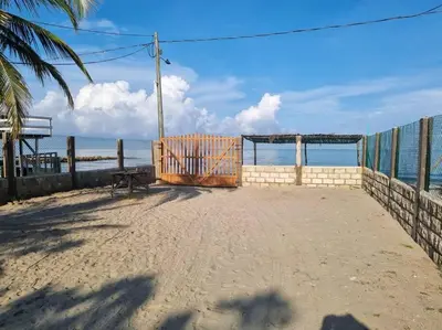 a gate on the beach with a bench and the ocean at Cabaña Lilimar. in La Perdiz