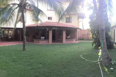 a house with a hose in a yard with palm trees at Casa de playa Nijegi en Santa Veronica in Juan de Acosta