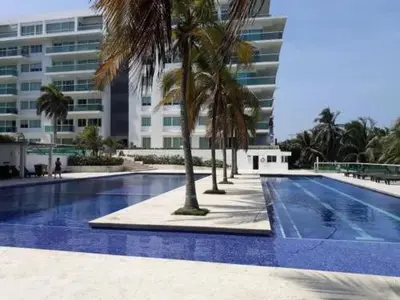 a swimming pool with palm trees in front of a building at Apartamento con terraza Frente al Mar in Cartagena de Indias