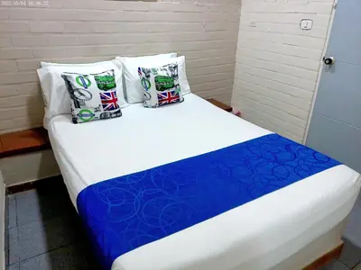 a bed with blue and white sheets and pillows at Hotel Casa Boston Inn by Finerh in Barranquilla