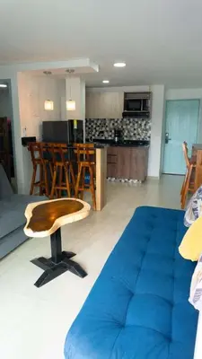 a living room with a blue couch and a kitchen at Apartamento en la Boquilla in Cartagena de Indias