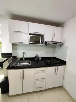 a kitchen with white cabinets and a sink and a microwave at APARTAMENTOS LOS MANGLARES marbella in Cartagena de Indias