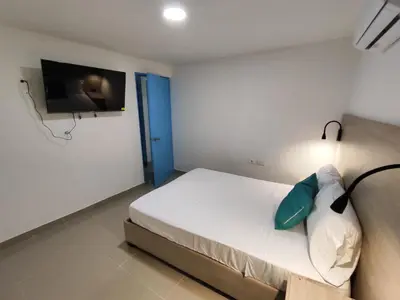 a bedroom with a bed with a tv on the wall at APARTAMENTOS LOS MANGLARES marbella in Cartagena de Indias