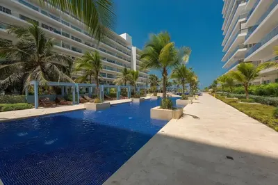 a resort swimming pool with palm trees and a building at Condominio frente al mar con acceso directo a la playa Morros Ultra in Cartagena de Indias