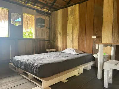 a bed in a room with a wooden wall at Punta Arena EcoHostal & EcoFit - Your Eco-Friendly Oasis in Playa Punta Arena