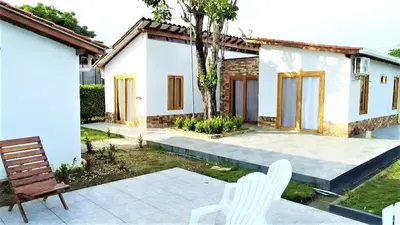 a patio with two white chairs and a house at Cabaña Maria José in Moñitos