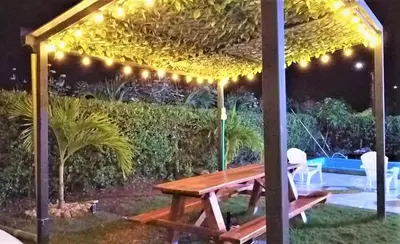a wooden picnic table under a pergola with lights at Cabaña Maria José in Moñitos