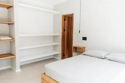 a bedroom with a white bed and shelves at Gaia Casa de Mar in El Bobo