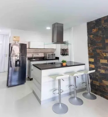 a kitchen with a refrigerator and two bar stools at Prime Location: Fully Equipped Loft in El Laguito in Cartagena de Indias