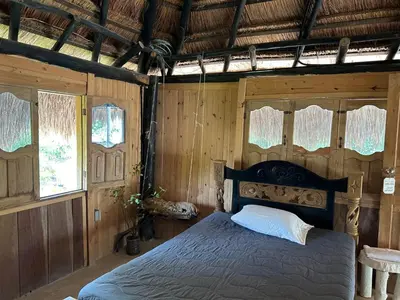 a bedroom with a bed in a room with wooden walls at Punta Arena EcoHostal & EcoFit in Playa Punta Arena