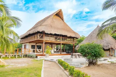 a hut with a thatched roof and a palm tree at U-GO Espectacular Casa en Barú con Vistas al Mar in Cartagena de Indias