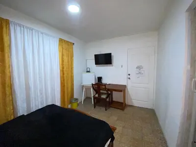 a bedroom with a bed and a desk and a door at Habitación Cerca de aeropuerto in Cartagena de Indias