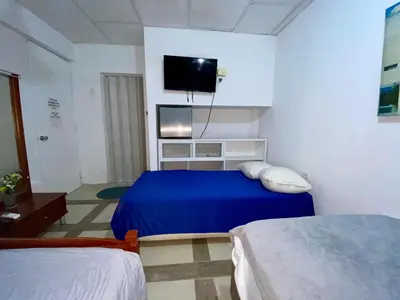 a bedroom with two beds and a tv on the wall at Habitación Multiple cerca de aeropuerto in Cartagena de Indias