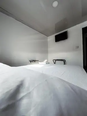 a white bed in a white room with a television at Hotel bazurto plaza in Cartagena de Indias