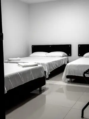 two beds in a room with white walls at Hotel bazurto plaza in Cartagena de Indias