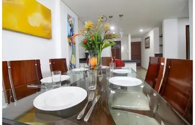 a dining room with a glass table with plates and flowers at Torres del lago de 3 habitaciones in Cartagena de Indias