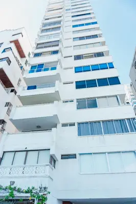 a tall white building with blue windows at Acogedor Apartaestudio Laguito 1 Habitacion N4A1 in Cartagena de Indias