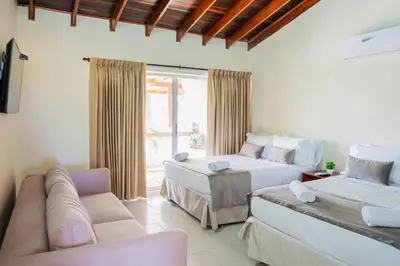 a living room with two beds and a couch at Hotel Playa Palmeras Cartagena - Vía al Mar in Cartagena de Indias