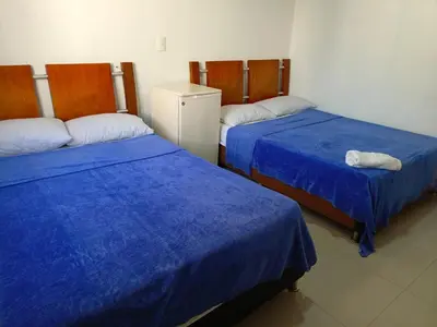 a room with two beds with blue sheets and a refrigerator at Hotel Palma Real Cartagena in Cartagena de Indias