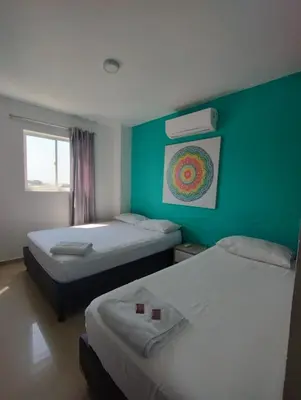 a room with two beds and a green wall at HOTEL BELLAMAR in Cartagena de Indias