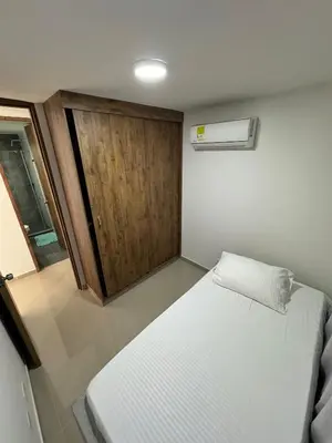 a small bedroom with a bed and a wooden door at Apto amoblado en Alameda del Río in Barranquilla