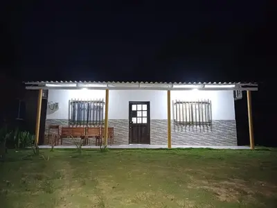 a white house with a bench in a yard at night at Cabaña Moñitos cerca al mar e Isla Fuerte in Moñitos
