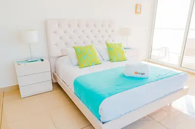 a white bed with a white headboard and pillows at U-GO Edificio H2 en Bocagrande Frente al Mar in Cartagena de Indias