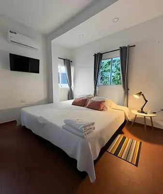 a white bedroom with a large white bed and a table at Céntrico y confortable apto Casa Doña yola 7 in Cartagena de Indias