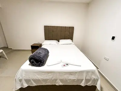 a bedroom with a large white bed with a black bag on it at Hotel & Restaurante Oasis CTG in Cartagena de Indias