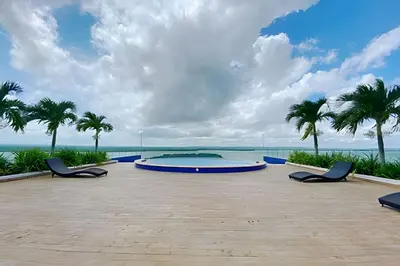 a large pool with chairs and palm trees and the ocean at Apartamento 2 Dormitorios Morros. Vista Mar in Cartagena de Indias