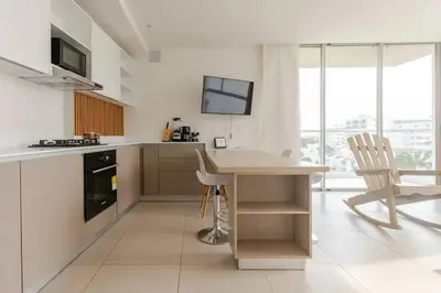 a white kitchen with a table and a chair at Encanto Rentals at Sunno Beach in Cartagena de Indias