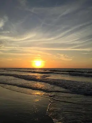 a sunset on a beach with the ocean at Pajarito Eco-Lodge frente al mar in Cedro