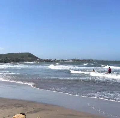 two people riding the waves on surfboards in the ocean at Espectacular casa en oferta con piscina privada y vista al mar in Carretal