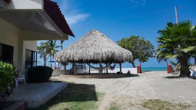 a straw hut on a beach with the ocean at Cabaña La Pereztroica 3 in Coveñitas